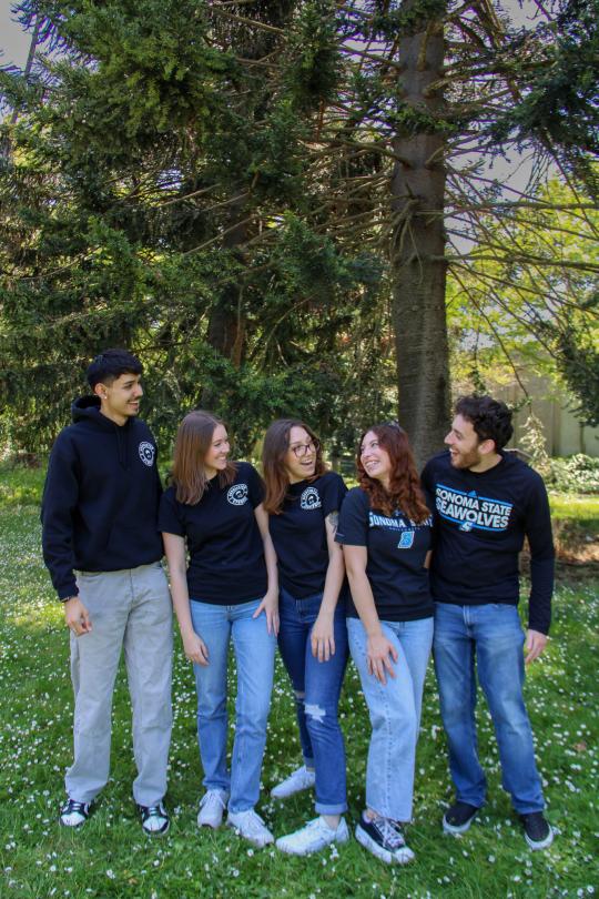 Five student staff members smiling at each other wearing AS sweatshirts