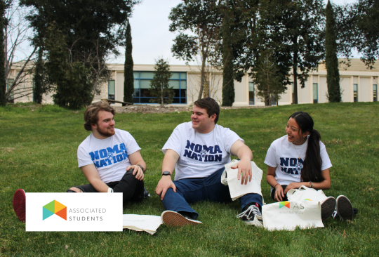 Three students on person lawn talking to each other.