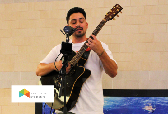 Man playing a guitar and singing into a mic.